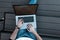 Blogger businessman guy in t-shirt in stylish jeans working on a modern laptop on the street. Top view of male hands with a laptop