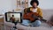 Blogger guitarist. African American girl blogger playing guitar talking to webcam recording vlog. Social media