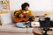 Blogger guitarist. African american girl blogger playing guitar talking to webcam recording vlog. Social media