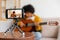 Blogger guitarist. Happy african american girl blogger playing guitar singing song recording vlog. Social media