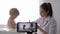 Blogging, popular vlogger female doctor filming new episode for vlog on smartphone during medical examination of baby