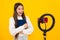 Blogging, videoblog. Teenager school girl blogger with phone recording video on isolated yellow studio background