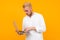 Blond attractive guy typing on laptop on yellow background