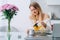 Blond attractive woman in kitchen pouring herb healthy citron tea teapot. Flower