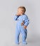 Blond baby boy toddler in blue cotton jumpsuit with rainbow and tiger stands with head turned watching back
