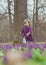 Blond baby in a colored dress running in a forest glade with flowers