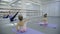 The blond ballet teacher leads the stratching with her two little students in the bright gym.