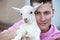 Blond bavarian man holding a little white goat