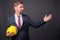 Blond bearded businessman with goatee holding hardhat against gr