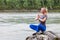 Blond beautiful girl sitting on the stone cliff ground resting after sport and doing yoga and meditation outdoors in the mountains