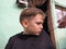 A blond boy of 8 years old gets his hair cut with scissors. Hairdresser services at home. Haircut for a child with blond hair