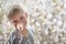 Blond boy in breathing mask inhaler on a background of flowering trees. Home treatment. Prevention