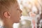 Blond boy in breathing mask inhaler on a background of flowering trees. Home treatment. Prevention. Close up