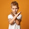 Blond boy child in white t-shirt and jeans standing and showing stop rejection sign by hands looking at camera