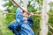 Blond boy climbing rope on the autumn playground outdoors