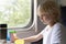 Blond boy in compartment carriage is having lunch. Traveling with child by train. Travel by railway