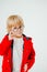 Blond boy with glasses. A beautiful blonde child. Boy in a red coat