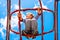 Blond boy perched on a web rope-ladder structure in a children`s playground for fun climbing