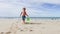 Blond boy run with toy bucket at ocean beach, pour water on sand