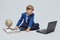 Blond boy in a school suit is sitting in front of a laptop, a globe, and a book. photo session in the Studio on a white background