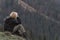 Blond boy sits at hillside and looks at the distance. Side view on boy in mountains. Vacation with children