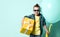 Blond boy in stylish casual clothing and sunglasses holding big yellow present box and big balloon