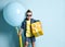 Blond boy in stylish casual clothing and sunglasses holding big yellow present box and big balloon