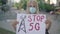 Blond Caucasian woman in face mask protesting against 5G mobile towers. Rack focus changes from female activist to