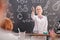 Blond cheerful teacher of chemistry in whitecoat pointing at one of schoolkids