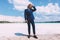 Blond curly man walking on the beach of crystal clear sea. Dressed business suit, blue color. Summer, trendy. Travel topic
