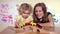Blond cute girl and her mother play with toy train and clap hands