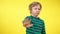 Blond cute kid gesturing no looking at camera. Portrait of little charming Caucasian boy posing at yellow background