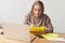 Blond European student girl with a laptop and paper sheets