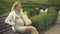Blond expecting lady resting bench holding grocery bag, pregnancy difficulties