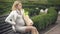 Blond expecting lady resting bench holding grocery bag, pregnancy difficulties