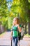 Blond explorer kid girl walking with backpack in autumn trees