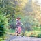 Blond fashionable long-haired attractive girl in short dress with lady bicycle in sunny park.