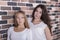 Blond girl and brunette in white shirts standing with serious faces