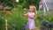 Blond girl in dress smell dill plant. Curious child exploring flora in garden