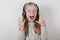 Blond girl with headphones listening music and singing. Cute little girl making a rock-n-roll sign.