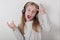 Blond girl with headphones listening music and singing. Cute little girl making a rock-n-roll sign.