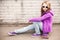 Blond girl in jeans and sunglasses sits on skateboard