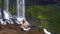 Blond girl sits in pranayama yoga pose on rock at waterfall