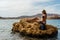 Blond girl sitting with scuba diving mask and fins on rock