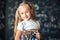 Blond girl standing near a black slate with a pile of books. Free space. Black background. School concept