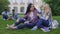 Blond girl supporting her best friend, students sitting on lawn near campus