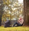 Blond girl texting by phone seated in park