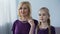 Blond grandmother and granddaughter with pearl necklaces looking in mirror