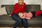 Blond hair mom in red sweater sitting on sofa with her daughter. Beautiful woman