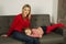 Blond hair mom in red sweater sitting on sofa with her daughter. Beautiful woman